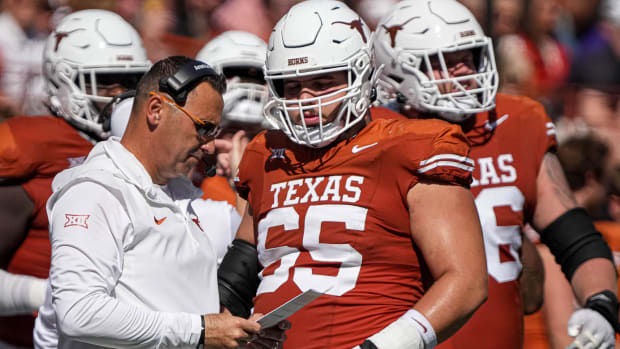 Texas Longhorns head coach Steve Sarkisian looks at his playbook with offensive lineman Jake Majors (65) during the game agai