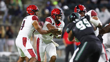 Nov 8, 2025; Honolulu, Hawaii, USA; San Diego State Aztecs quarterback Jayden Denegal (4) hands the ball to running back Lucky Sutton (7) as they take on the Hawaii Rainbow Warriors in the first quarter at Clarence T.C. Ching Athletics Complex.