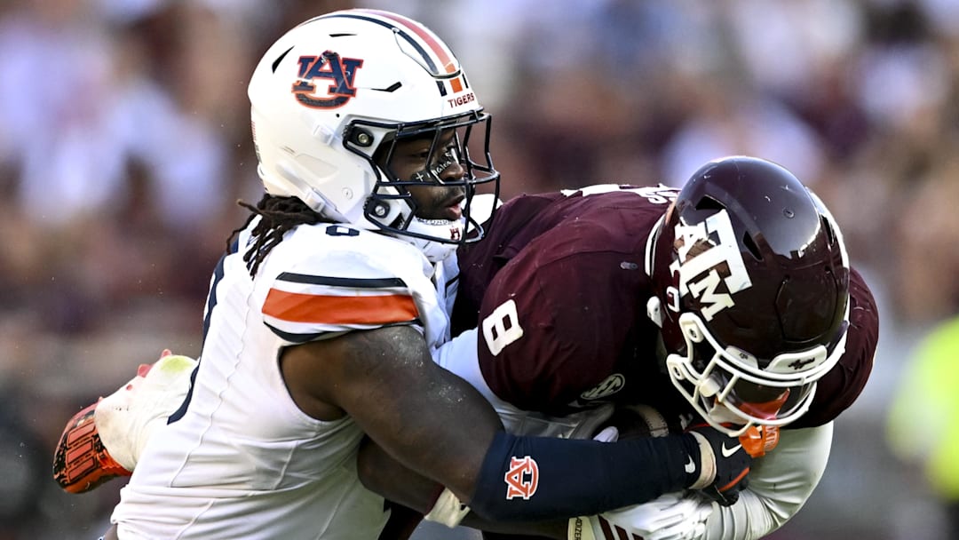 Sep 27, 2025; College Station, Texas, USA; Auburn Tigers linebacker Robert Woodyard Jr. (0) wraps up Texas A&M Aggies running back Le'Veon Moss (8) during the third quarter at Kyle Field. Mandatory Credit: Maria Lysaker-Imagn Images