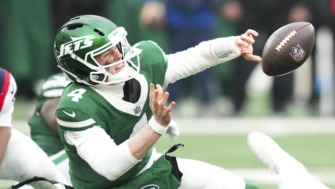 New York Jets quarterback Brady Cook (4) gets the ball off for an incomplete pass as he is tackled by New England Patriots linebacker Anfernee Jennings (33) during the second half of the game at MetLife Stadium. 