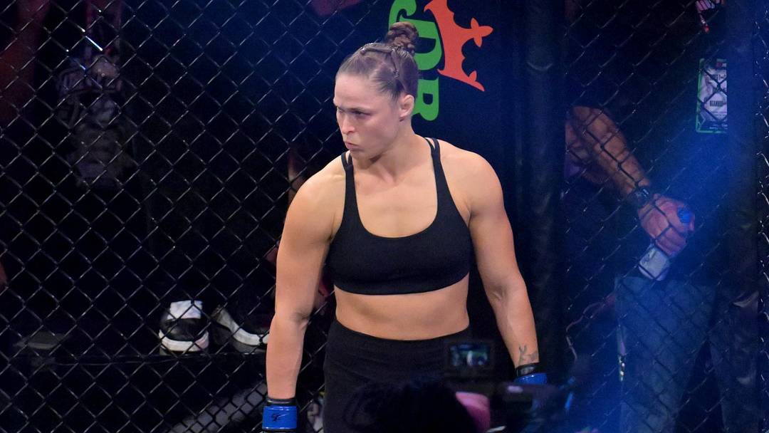 May 16, 2026; Los Angeles, California, USA;  Ronda Rousey (blue gloves) looks on before fighting Gina Carano (red gloves) in a women's featherweight bout at Intuit Dome. Mandatory Credit: Jayne Kamin-Oncea-Imagn Images