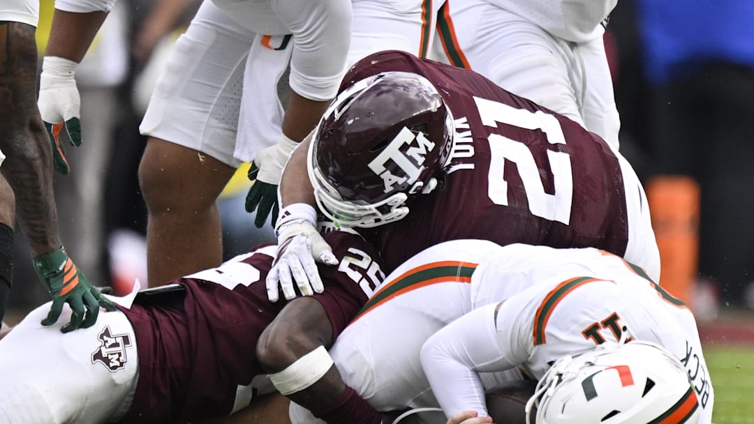Texas A&M Aggies safety Dalton Brooks (25) and linebacker Taurean York (21) sack Miami Hurricanes quarterback Carson Beck (11) during first half of the first round game of the CFP National Playoff at Kyle Field. 