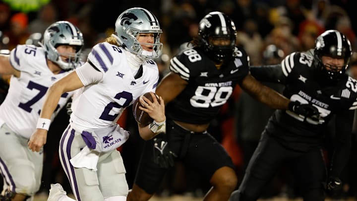 Quarterback Avery Johnson #2 of the Kansas State Wildcats scrambles for yards as defensive tackle Holden Bass #75 of the Kansas State Wildcats, blocks as defensive end Trent Jones II #89, and linebacker Will McLaughlin #23 of the Iowa State Cyclones defend in the first half of play at Jack Trice Stadium on November 30, 2024, in Ames, Iowa.