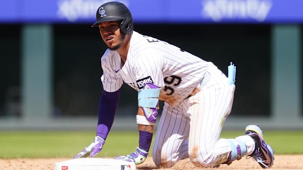 Colorado Rockies second baseman Thairo Estrada kneels in a white uniform and black helmet
