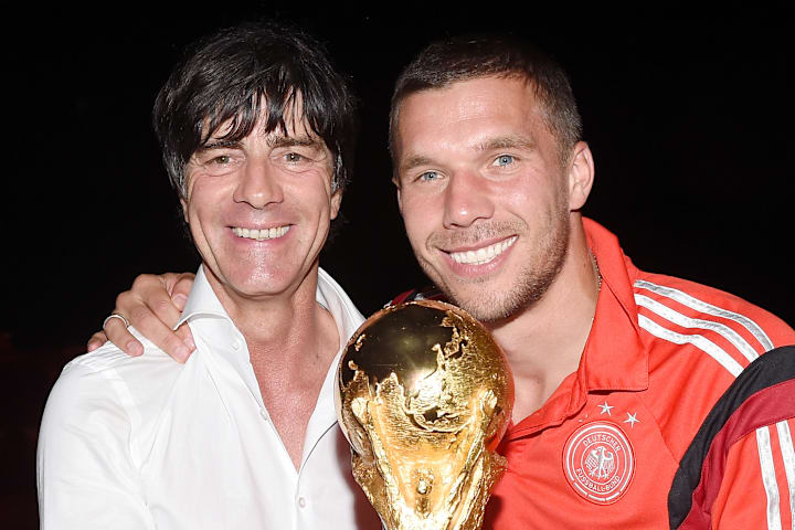 Jogi Löw mit Lukas Podolski und dem Weltmeisterpokal 2014