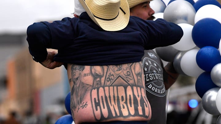 A Dallas Cowboys fan shows off his tattoos to the crowd from a float. A Dallas Cowboys fan shows off his tattoos to the crowd from a float.