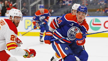 Sep 23, 2024; Edmonton, Alberta, CAN; Edmonton Oilers forward Connor Clattenburg (64) and Calgary Flames defensemen Jarred Tinordi (26) chase a loose puck during the first period at Rogers Place. Mandatory Credit: Perry Nelson-Imagn Images