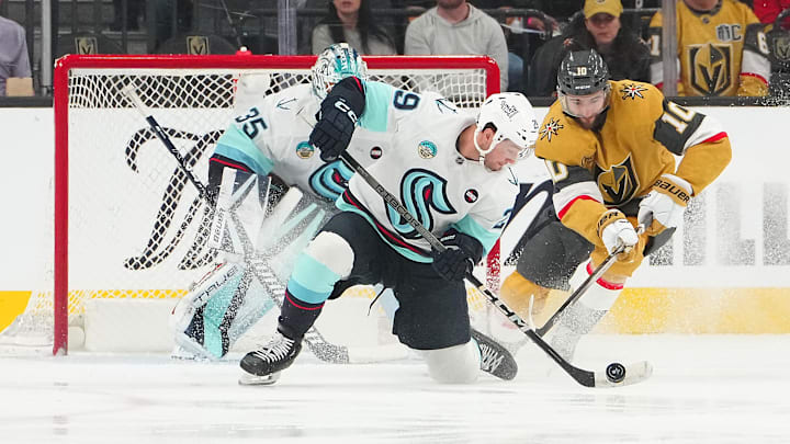 Apr 10, 2025; Las Vegas, Nevada, USA; Seattle Kraken defenseman Vince Dunn (29) clears the puck away from Vegas Golden Knights center Nicolas Roy (10) in front of Seattle Kraken goaltender Joey Daccord (35) during the first period at T-Mobile Arena. Mandatory Credit: Stephen R. Sylvanie-Imagn Images