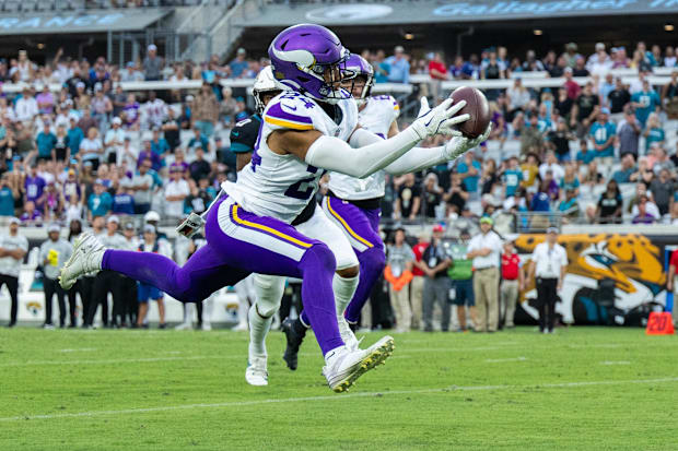 Minnesota Vikings safety Camryn Bynum (24) makes the interception against the Jacksonville Jaguars in a white jersey.