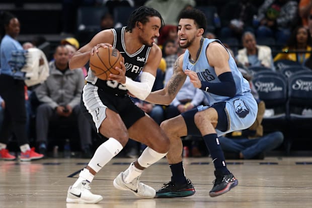 San Antonio Spurs guard Tre Jones (33) handles the ball while Memphis Grizzlies guard Scotty Pippen Jr. (1) defends it.