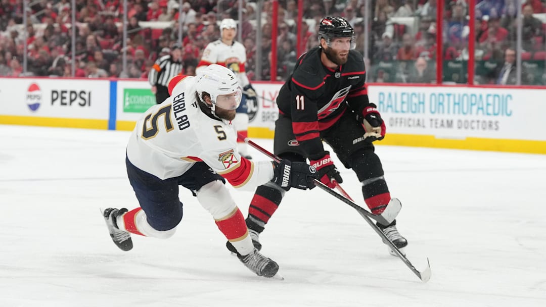 May 20, 2025; Raleigh, North Carolina, USA;  Florida Panthers defenseman Aaron Ekblad (5) shoots as Carolina Hurricanes forward Jordan Staal (11) defends during the second period in game one of the Eastern Conference Final of the 2025 Stanley Cup Playoffs at Lenovo Center. Mandatory Credit: James Guillory-Imagn Images