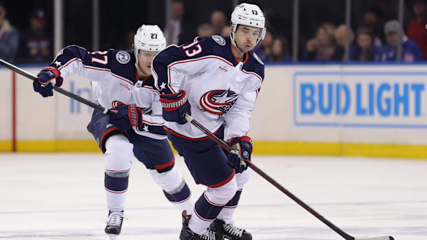 hockey player in white uniform skates with the puc