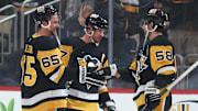 Mar 30, 2025; Pittsburgh, Pennsylvania, USA;  Pittsburgh Penguins defenseman Erik Karlsson (65) and center Sidney Crosby (middle) and defenseman Kris Letang (58) celebrate after defeating the Ottawa Senators in overtime at PPG Paints Arena. Mandatory Credit: Charles LeClaire-Imagn Images