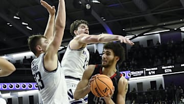 Dec 29, 2024; Evanston, Illinois, USA;  Northeastern Huskies center Collin Metcalf (45) shoots against Northwestern Wildcats forward Luke Hunger (33) and guard Brooks Barnhizer (13) during the first half at Welsh-Ryan Arena. Mandatory Credit: Matt Marton-Imagn Images
