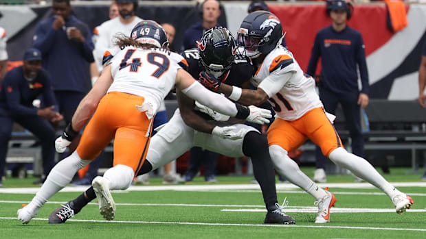 Nico Collins (12) is tackled by Denver Broncos linebacker Alex Singleton (49) and cornerback Kris Abrams-Draine. 