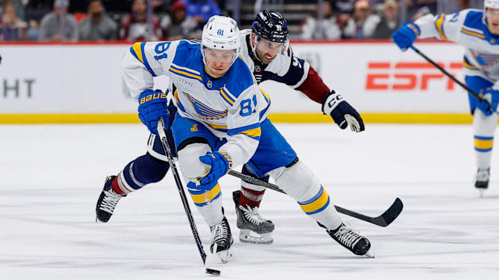 Apr 5, 2026; Denver, Colorado, USA; St. Louis Blues left wing Dylan Holloway (81) controls the puck ahead of Colorado Avalanche center Nazem Kadri (91) in the first period at Ball Arena. Mandatory Credit: Isaiah J. Downing-Imagn Images