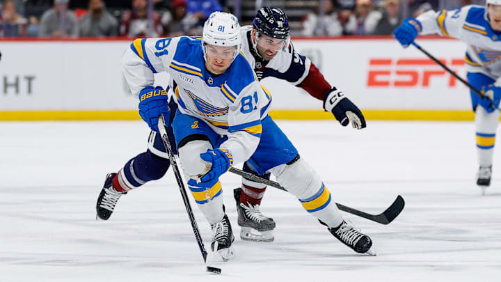 Apr 5, 2026; Denver, Colorado, USA; St. Louis Blues left wing Dylan Holloway (81) controls the puck ahead of Colorado Avalanche center Nazem Kadri (91) in the first period at Ball Arena. Mandatory Credit: Isaiah J. Downing-Imagn Images