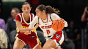Nov 9, 2025; Charlotte, North Carolina, USA; NC State Wolfpack guard Devyn Quigley (0) battles for position against Southern California Trojans guard Jazzy Davidson (9) during the third quarter of the Ally Tipoff game at Spectrum Center. Mandatory Credit: Cory Knowlton-Imagn Images