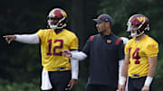 Jul 27, 2023; Ashburn, VA, USA; Washington Commanders quarterbacks coach Tavita Pritchard (M) talks with Washington Commanders quarterbacks Jacoby Brissett (12) and Sam Howell (14) during day two of Commanders training camp at OrthoVirginia Training Center. Mandatory Credit: Geoff Burke-Imagn Images