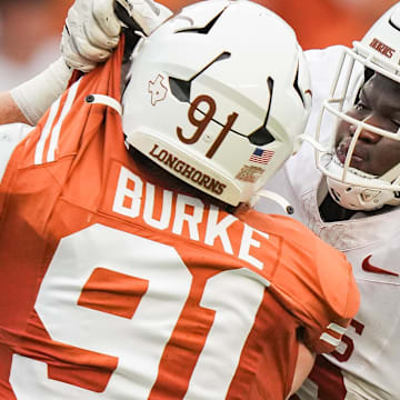 April 20, 2024; Austin, Texas, USA: Texas White team offensive lineman Cameron Williams (56) grabs the uniform of Texas Orange team edge Ethan Burke (91) in the second quarter of the Longhorns' spring Orange and White game at Darrell K Royal Texas Memorial Stadium. Mandatory Credit: Sara Diggins-Imagn Images via American Statesman