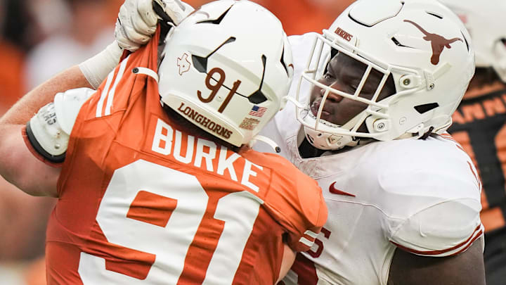 April 20, 2024; Austin, Texas, USA: Texas White team offensive lineman Cameron Williams (56) grabs the uniform of Texas Orange team edge Ethan Burke (91) in the second quarter of the Longhorns' spring Orange and White game at Darrell K Royal Texas Memorial Stadium. Mandatory Credit: Sara Diggins-Imagn Images via American Statesman