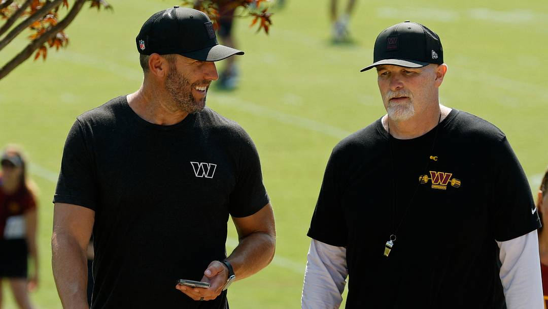 Jul 24, 2025; Ashburn, VA, USA; Washington Commanders general manager Adam Peters (L) talks with Commanders head coach Dan Quinn (R) while walking off the practice field on day two of training camp at OrthoVirginia Training Center at Commanders Park. Mandatory Credit: Geoff Burke-Imagn Images