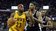 Nov 19, 2014; Cleveland, OH, USA; Cleveland Cavaliers forward LeBron James (23) drives against San Antonio Spurs forward Tim Duncan (21) and forward Kawhi Leonard (2) in the second quarter at Quicken Loans Arena. Mandatory Credit: David Richard-Imagn Images
