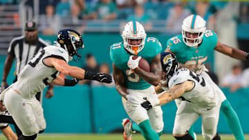 Aug 23, 2025; Miami Gardens, Florida, USA; Miami Dolphins running back Ollie Gordon II (31) runs with the football past Jacksonville Jaguars linebacker Dennis Gardeck (57) and linebacker Branson Combs (50) during the second quarter at Hard Rock Stadium. Mandatory Credit: Sam Navarro-Imagn Images
