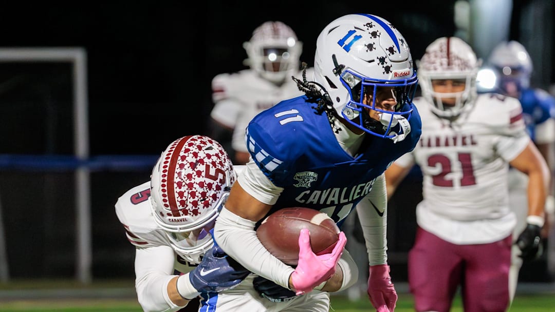 Caravel defensive back Richie Massey (left) dives to bring down Middletown receiver DJ Davis after a catch and run in the first quarter of the Cavaliers’ 28-7 win over the Buccaneers at Cavalier Stadium on Oct. 17, 2025.