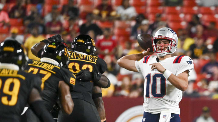 Aug 25, 2024; Landover, Maryland, USA;  New England Patriots quarterback Drake Maye (10) throws off his back foot as Washington Commanders defense applies pressure during the first half at Commanders Field. Mandatory Credit: Tommy Gilligan-USA TODAY Sports