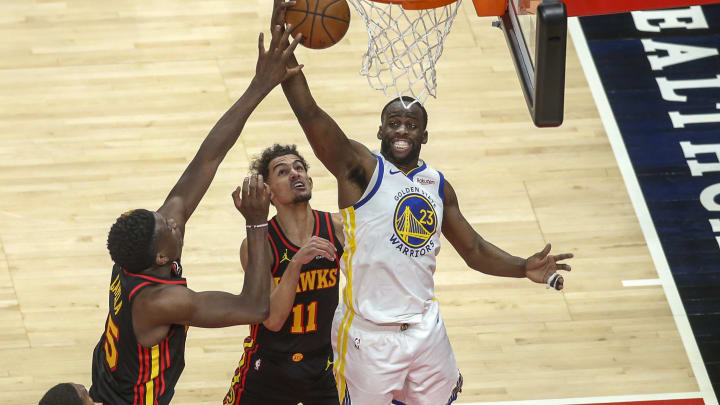 Apr 4, 2021; Atlanta, Georgia, USA; Golden State Warriors forward Draymond Green (23) grabs a rebound over Atlanta Hawks center Clint Capela (15) and guard Trae Young (11) in the second quarter at State Farm Arena. 