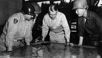 United States Army Chief of Staff General Collins studying a map of the front line during the battle for Korea, with Lieutenant General Walker, Brigadier General Farrell, and Korean Brigadier General Paik.
