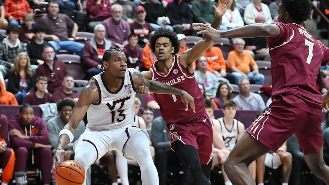 Feb 14, 2026; Blacksburg, Virginia, USA; Virginia Tech Hokies forward Amani Hansberry (13) drives the baseline defended by Florida State Seminoles guard Martin Somerville (1) during the second half at Cassell Coliseum. Mandatory Credit: Brian Bishop-Imagn Images