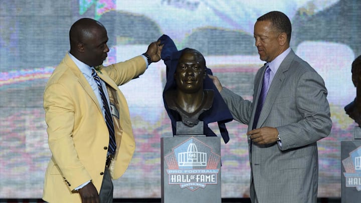 August 3, 2011; Canton, OH, USA; Marshall Faulk (left) is presented his bust by Rocky Arceneaux (right) at the 2011 Pro Football Hall of Fame enshrinement at Fawcett Stadium. Mandatory Credit: Rick Osentoski-Imagn Images