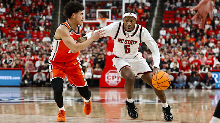 Jan 27, 2026; Raleigh, North Carolina, USA; NC State Wolfpack guard Tre Holloman (5) dribbles with the ball guarded by Syracuse Orange guard Naithan George (11) during the first half of the game at Lenovo Center. Mandatory Credit: Jaylynn Nash-Imagn Images