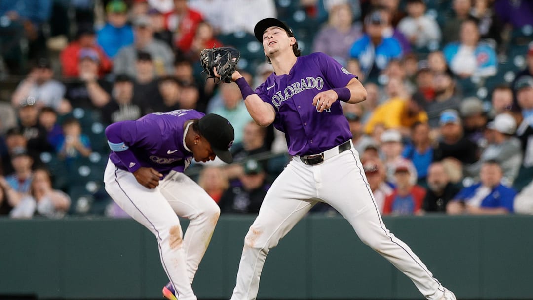 May 20, 2025; Denver, Colorado, USA; Colorado Rockies first baseman Michael Toglia (4) makes a catch over second baseman Adael Amador (1) in the fifth inning against the Philadelphia Phillies at Coors Field. 