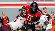 Sep 27, 2025; Raleigh, North Carolina, USA;  North Carolina State Wolfpack quarterback CJ Bailey (11) attempts to run the ball but tackled by Virginia Tech Hokies defensive lineman Ben Bell (33) and linebacker Jaden Keller (24)  during the first half of the game at Carter-Finley Stadium. Mandatory Credit: Jaylynn Nash-Imagn Images