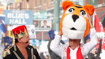 Wearing an Elvis Presley costume, Lee Corso dons the head of the Memphis Tigers mascot alongside wrestler Jerry Lawler.