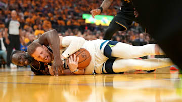 May 12, 2025; San Francisco, California, USA; Minnesota Timberwolves guard Donte DiVincenzo (0) gains control of a loose ball next to Golden State Warriors forward Draymond Green (23) in the second quarter during game four of the second round for the 2025 NBA Playoffs at Chase Center. Mandatory Credit: Cary Edmondson-Imagn Images
