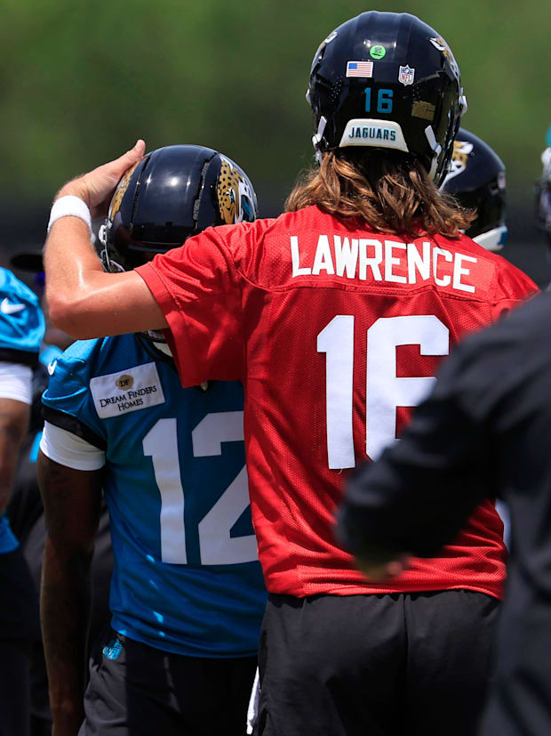 Jacksonville Jaguars quarterback Trevor Lawrence (16) taps wide receiver Travis Hunter (12) on the helmet as wide receiver Ca