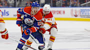 Sep 23, 2024; Edmonton, Alberta, CAN; Calgary Flames forward Kevin Rooney (21) tries to knock the puck away from Edmonton Oilers forward Connor McDavid (97) during the third period  at Rogers Place. Mandatory Credit: Perry Nelson-Imagn Images