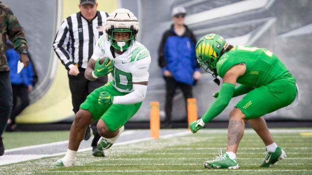 Oregon White Team running back Jordan James looks for a gap under cover from defensive back Kobe Savage