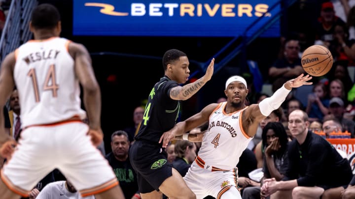 Apr 5, 2024; New Orleans, Louisiana, USA; San Antonio Spurs guard Devonte' Graham (4) passes the ball against New Orleans Pelicans guard Jordan Hawkins (24) during the first half at Smoothie King Center. Mandatory Credit: Stephen Lew-USA TODAY Sports