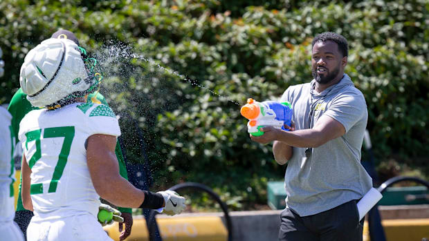 Oregon running backs coach Ra'Shaad Samples sprays running back Jayden Limar