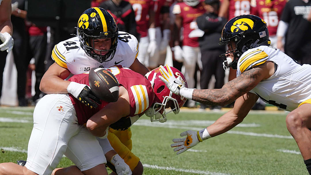 Iowa State Cyclones' running back Carson Hansen (26) looses the ball as getting tackler by Iowa Hawkeyes linebacker Jaden Harrell (41) and defensive back TJ Hall (2) during the first quarter in the Cy-Hawk Series at Jack Trice Stadium on Sept. 6, 2025, in Ames, Iowa