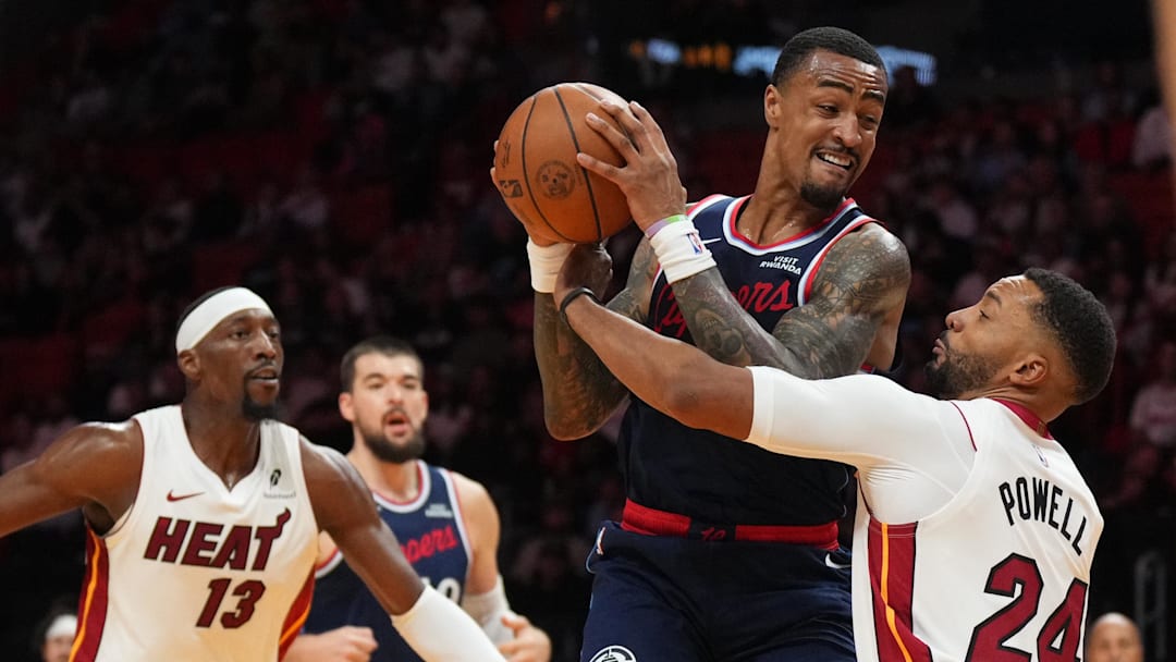 Dec 1, 2025; Miami, Florida, USA; Los Angeles Clippers forward John Collins (20) grabs a rebound over Miami Heat guard Norman Powell (24) during the first half at Kaseya Center. Mandatory Credit: Jim Rassol-Imagn Images