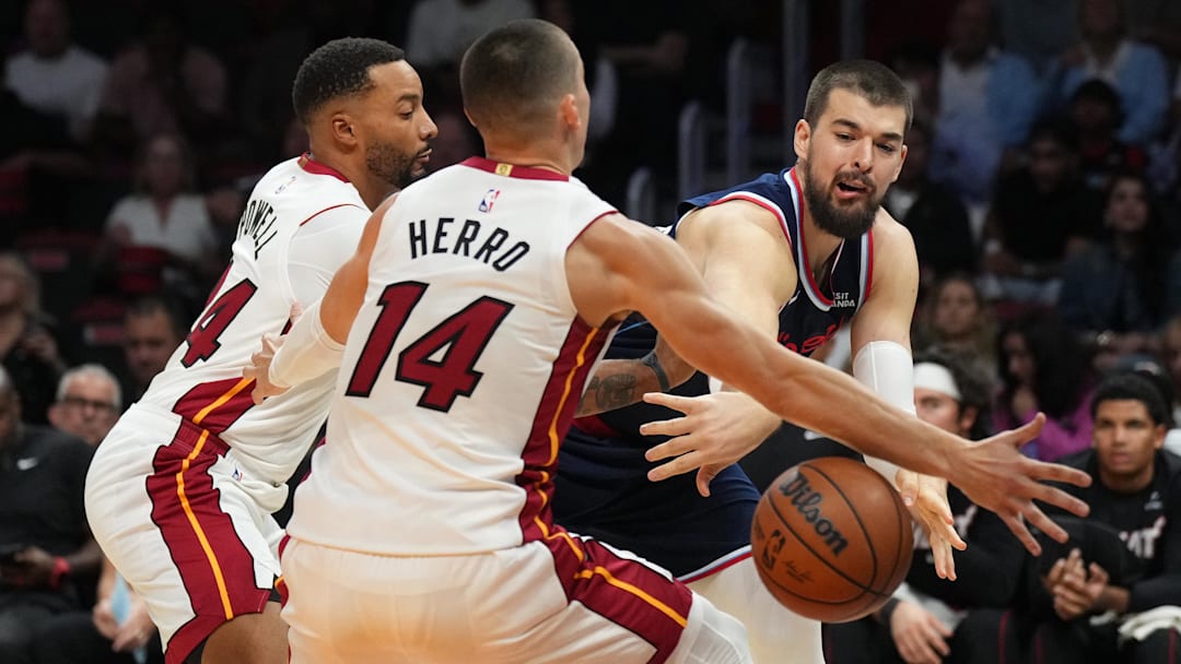 Dec 1, 2025; Miami, Florida, USA; Los Angeles Clippers center Ivica Zubac (40) makes a pass around Miami Heat guard Tyler Herro (14) and guard Norman Powell (24) during the first half at Kaseya Center. Mandatory Credit: Jim Rassol-Imagn Images