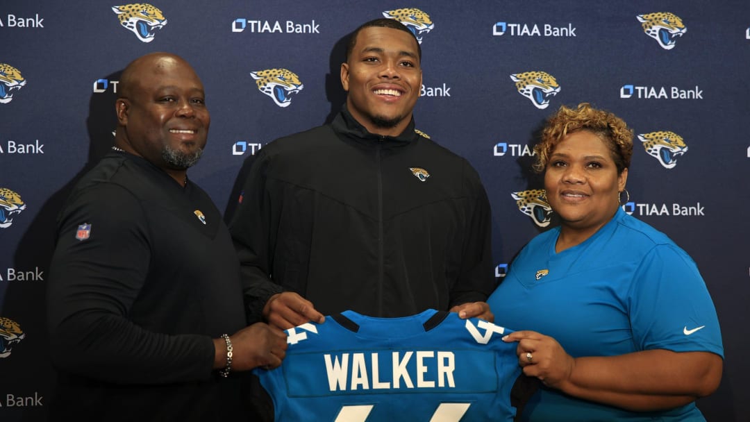 Jacksonville Jaguars first round NFL football draft pick Travon Walker, center, is flanked by his