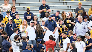 Rich Rodriguez in the stands with WVU fans and the 2025 Gold-Blue Spring Showcase at Milan Puskar Stadium in Morgantown.