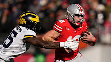 Ohio State Buckeyes quarterback Will Howard (18) runs past Michigan Wolverines linebacker Ernest Hausmann (15) during the NCAA football game at Ohio Stadium in Columbus on Tuesday, Dec. 3, 2024. Michigan won 13-10.